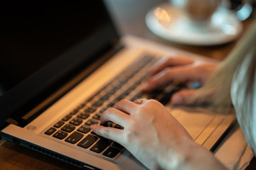 Close up hand of business woman working with laptop in coffee shop cafe,Warm tone,Selective focus