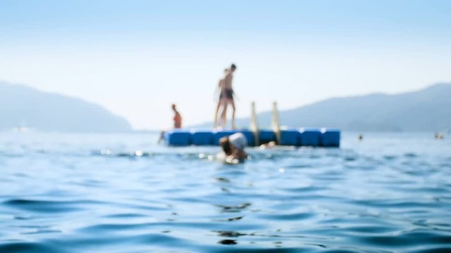4k out of focus footage of people relaxing on floating pantoon in the sea