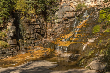 mountain waterfall over striated rock with pine trees