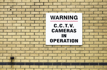 CCTV camera in operation sign on brick wall