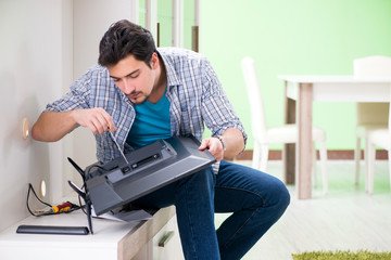 Young man husband repairing tv at home 