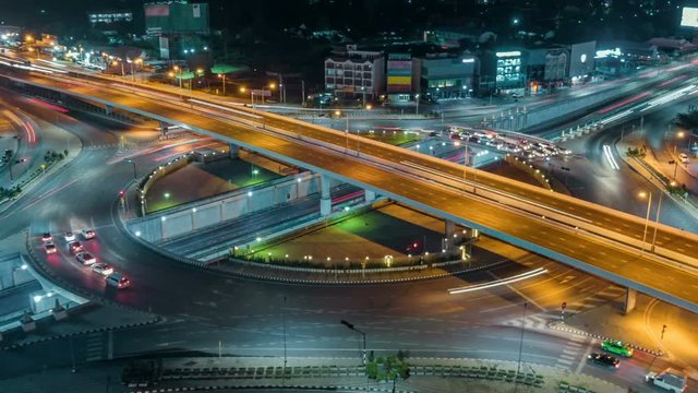 timelapse of night city traffic on 4-way stop street intersection circle roundabout in bangkok at night, thailand. 4K UHD horizontal aerial view.