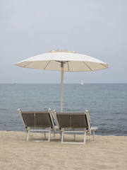 Weißer Sonnenschirm und Liegen am Strand mit Blick auf das Mittelmeer, Elba, Italien