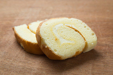 Slices of vanilla roll cake on wooden table.