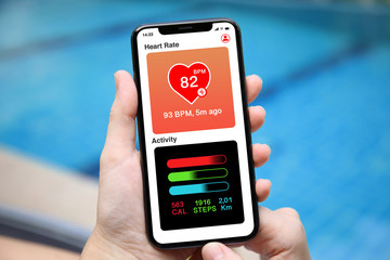 female hands holding phone with app heart and activity screen