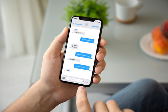 man hand holding phone with app messenger on the screen