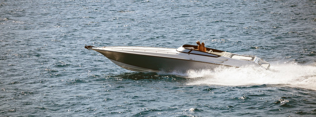 High-speed boat goes fast in calm sea. People enjoy the summer sport. Panoramic view, banner.