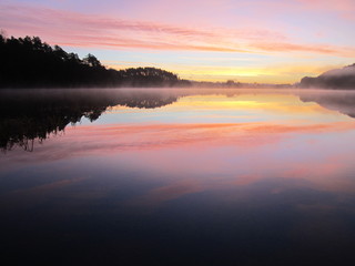 Sunrise in the forest over the mountains lake