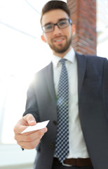 Fototapeta premium Businessman giving a card. Close-up photo in loft office