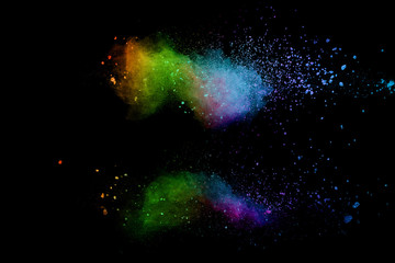 Abstract multicolored powder explosion on black background. Color dust particle splattered on background.