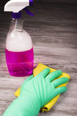 Cleaning items, hand in a green glove holding a yellow rag on the background of the washer