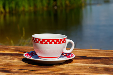 Cup of coffee on the wooden table near the river