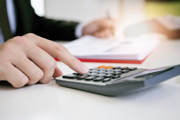 Closeup image of businessman hands pressing calculator buttons.