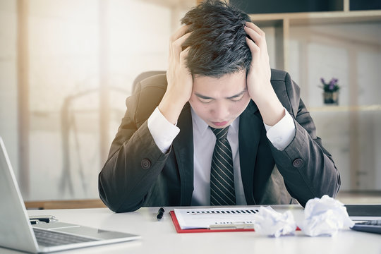 Tired frustrated young businesssman feeling stressed, holding head and worried about business problem