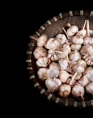 Organic garlic bulbs with garlic cloves in bamboo basket with black background,herb