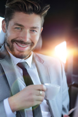 Businessman drinking coffee in the back seat of a car