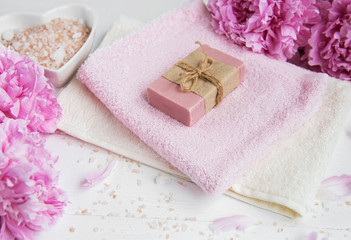 Fototapeta na wymiar bars of handmade soap, soft towels and peony flowers