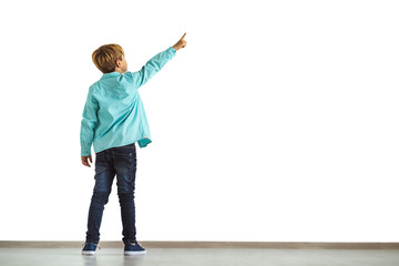 The little boy gesturing on the white wall background © Artem