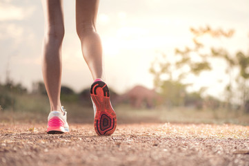 Runner feet running on rough road closeup on shoe. woman fitness sunrise jog concept...
