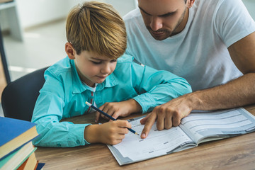 The father and a boy doing homework at the desk