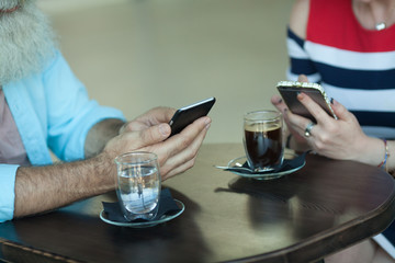 Close-up Of Two People Hands using smartphone.