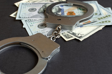 Illegal money concept. Selective focus. Handcuffs and currency on black color background.