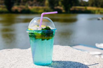 Mojito cocktail with lemon, ice and leaves of mint on a background of river
