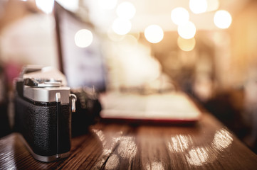 Camera on wood bar in coffee shop with blur background.