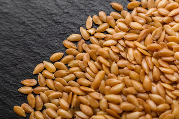 seeds of golden flax on a dark stone background