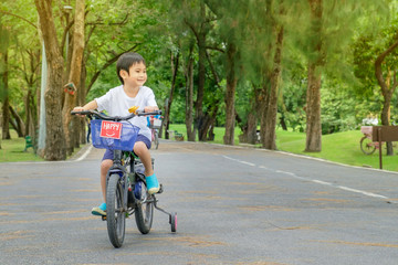 Fototapeta na wymiar Asian cute boy ride a bicycle at park green nature background.Copy Space Image.