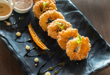 crispy calamari rings,deep fried calamari on black plate on wooden table