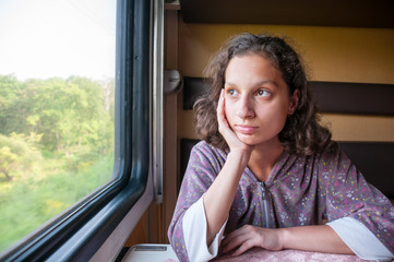 Teen girl sitting in compartment car of train in summer, traveling