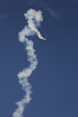 A stunt plane spiraling and leaving a smoke trail.