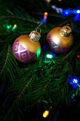 Shiny balls on a Christmas tree among colorful lights. Congratulations on the New Year and Christmas. Vertical frame.