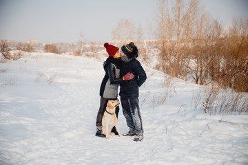 Fototapeta na wymiar Man and young woman play with labrador in winter, wearing winter hat and jacket. Concept of love and friendship, walk