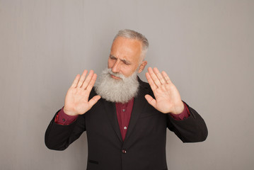 Senior man annoyed with bad attitude making stop sign with hand, saying no, expressing security,...