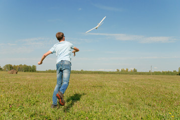 Hansome teenager  throwing DIY glider in the grass. Dream conception photo.