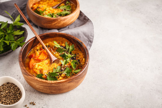 Yellow Indian vegan lentil soup curry with parsley and sesame in a wooden bowl, copy space.