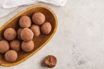 Raw vegan balls from nuts and cocoa in a wooden bowl, top view, copy space.