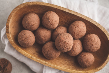 Raw vegan balls from nuts and cocoa in a wooden bowl, top view.