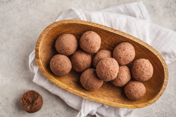 Raw vegan balls from nuts and cocoa in a wooden bowl, top view.