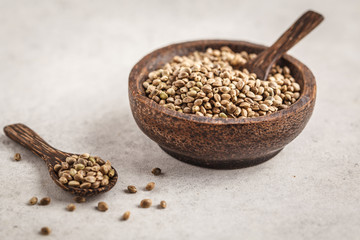 Wooden bowl of untreated hemp seeds. White background, copy space.