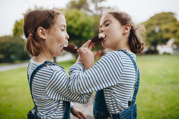 Twin sisters enjoying eating candy icecream