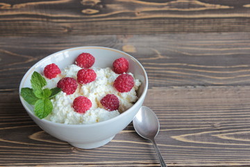 Cottage cheese with raspberries in a white bowl, a healthy dessert.