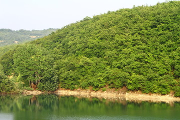 Fototapeta na wymiar beautiful still lake with green hills in distance. natural landscape photo.
