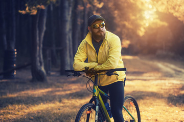 Naklejka premium bearded man cyclist rides in the forest on a mountain bike.