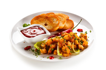 Grilled chicken nuggets and vegetables on white background