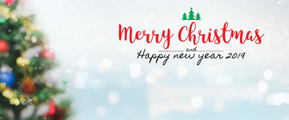 Fototapeta na wymiar Christmas and Happy new year 2019 on blurred bokeh christmas tree banner background with snowfall.
