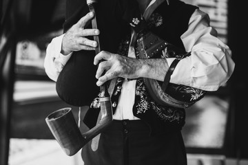 Older man plays bagpipes in folk costumes, close up