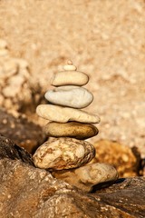 Fototapeta na wymiar Pebble stack on the seashore. Pyramid of stones on the beach. Light at sunset. Symbol of patience. Concept of harmony and balance. Memory of the sea.